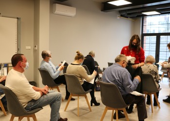 Trzech mężczyzn i trzy kobiety siedzą na krzesłach. Dwie kobiety stoją. Wszyscy mają maseczki.