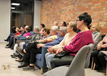 Grupa ludzi siedzi patrząc w jednym kierunku