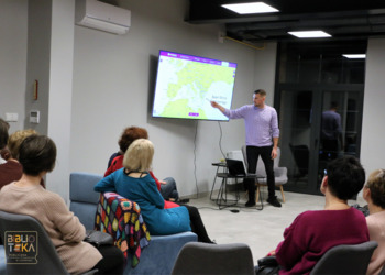 Mężczyzna pokazuje na mapie wyświetlanej na telewiorze