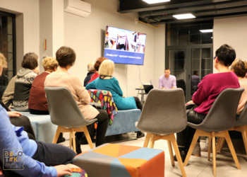 Grupa ludzi siedzi patrząc w jednym kierunku